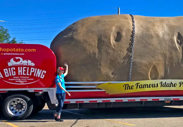 Woman standing in front of truck potato to show scale